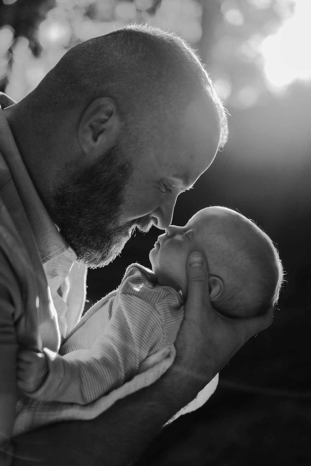 Black and white photo of a dad nose to nose with his baby