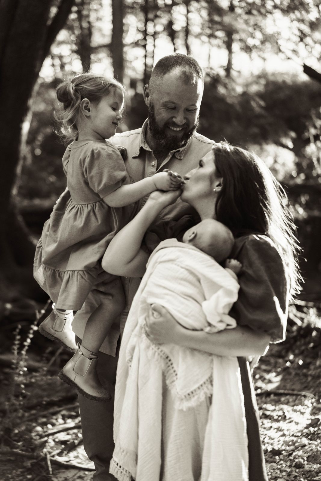 Black and white photo of a family hugging under the trees