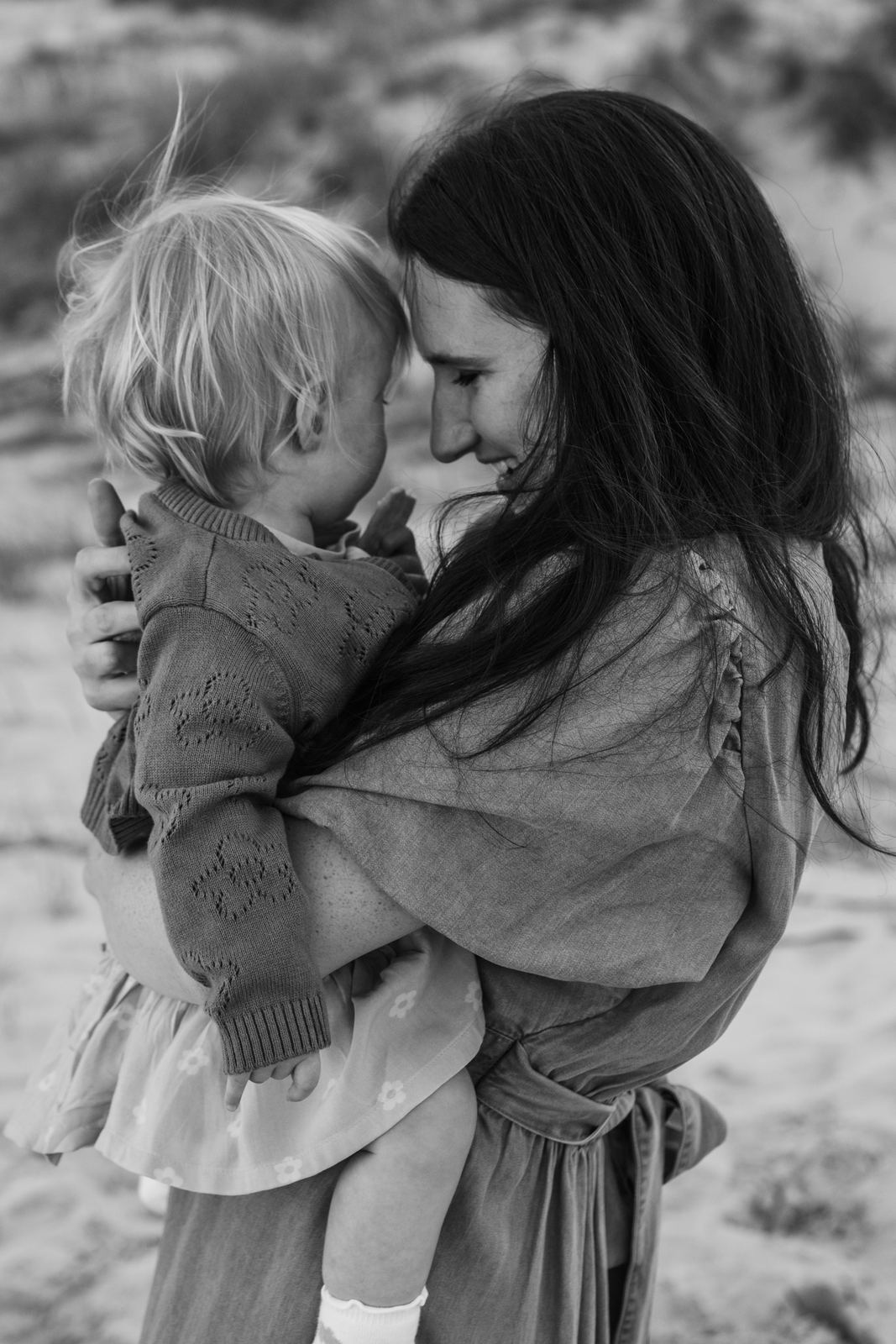 Black and white photo of a mum holding her toddler on her hip, foreheads touching