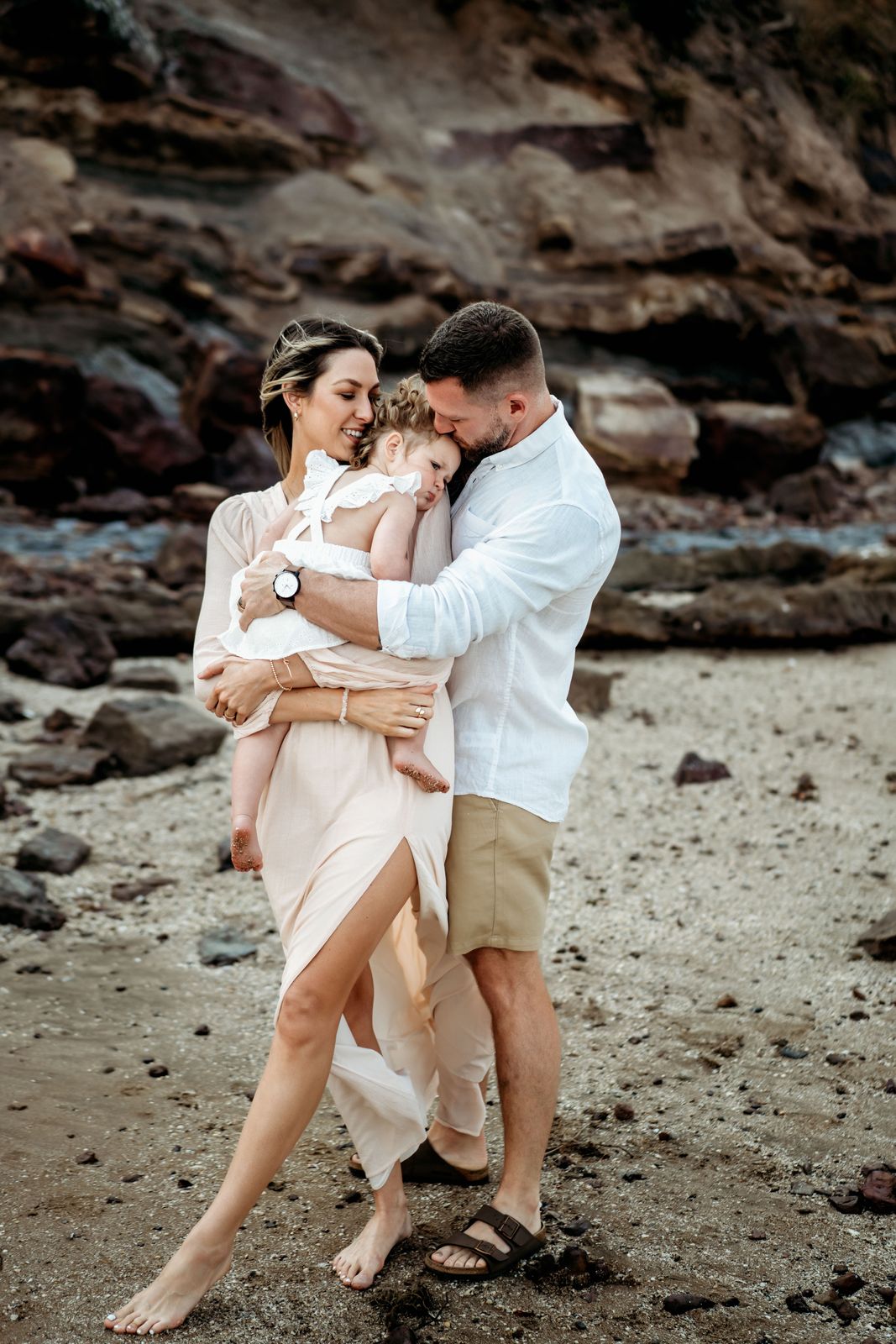 Couple holding their toddler between them on the beach