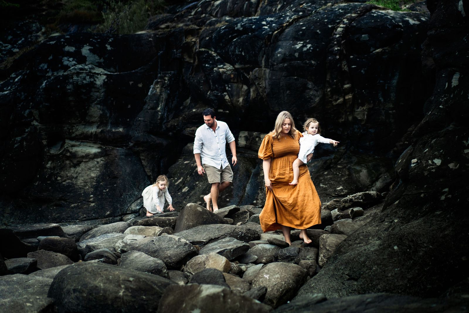 Family exploring the dark rocks at the beach together