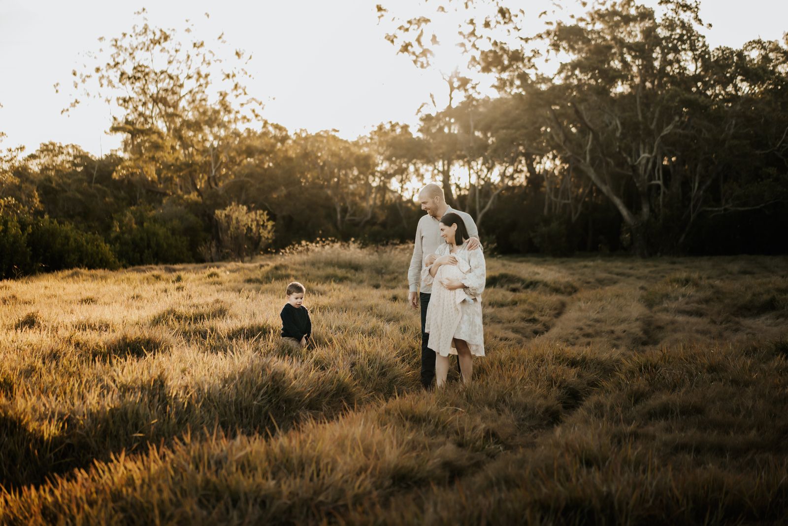 Family standing in an open field at golden hour