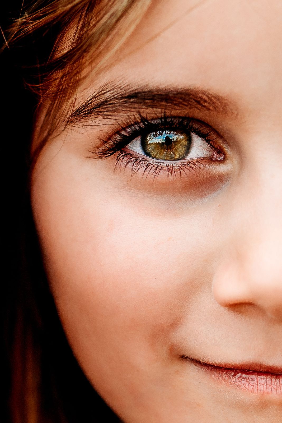 Close-up of a little girl's eye and freckles in warm light