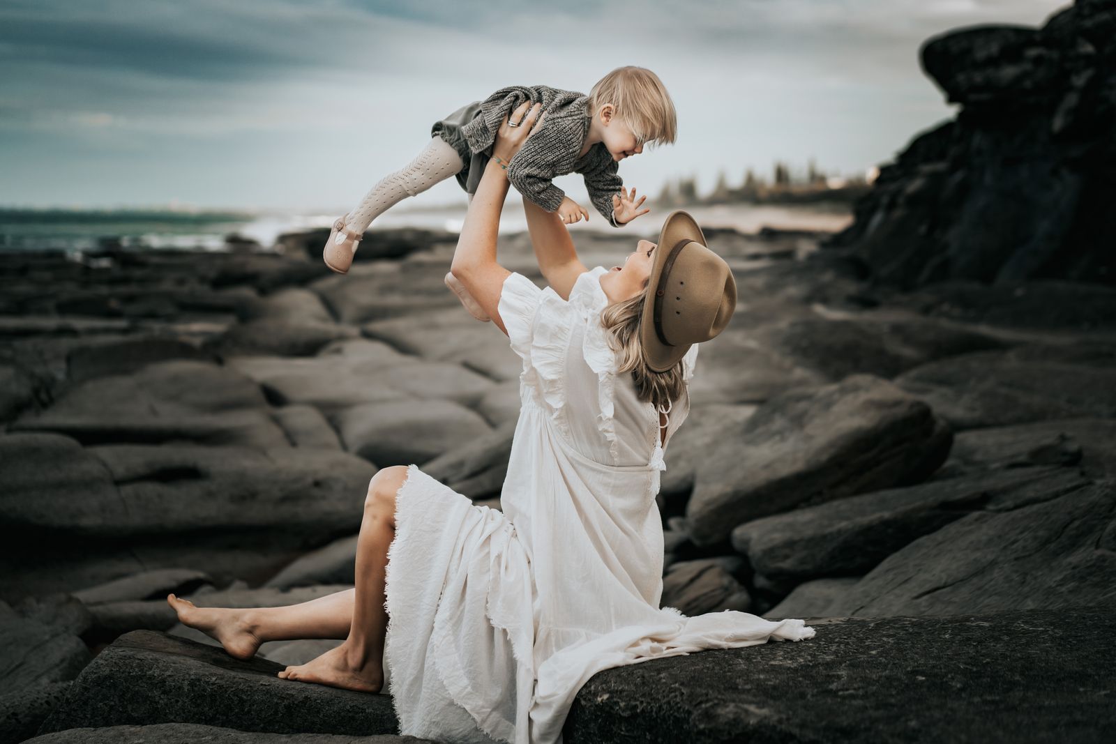 Mum lifting her little one high on the rock shelf