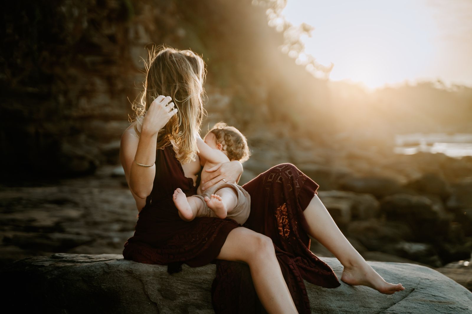 Mum and toddler snuggled on the rocks as the sun goes down