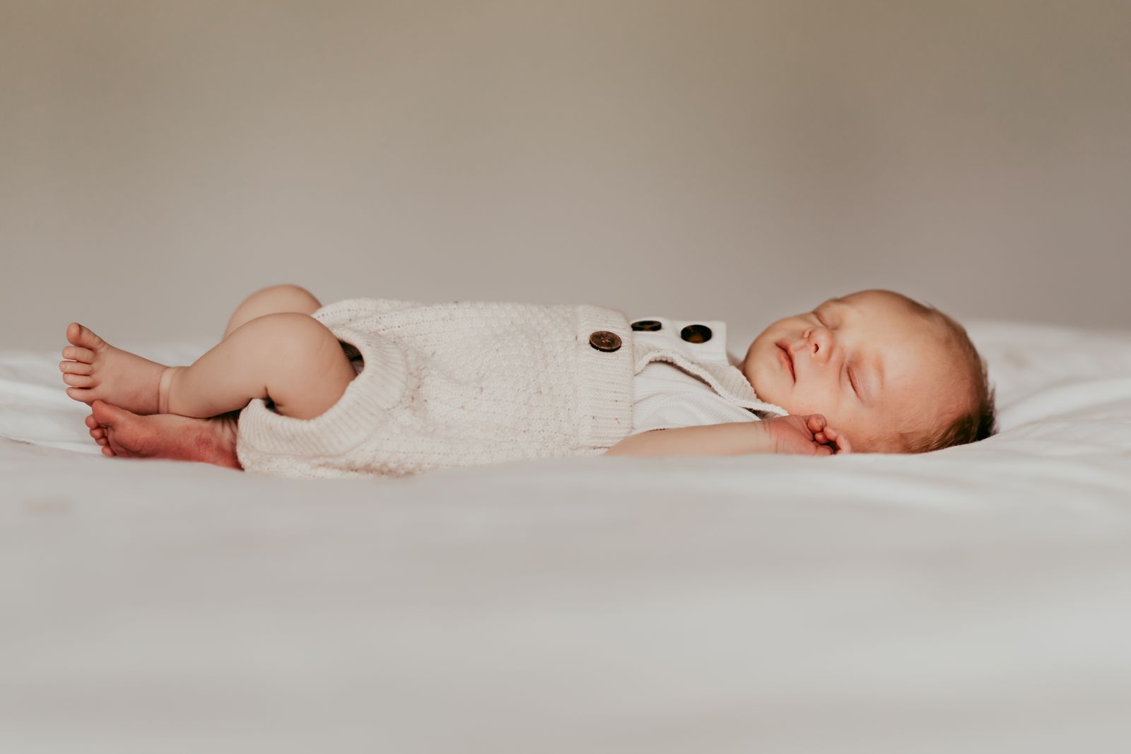 Newborn baby asleep on a soft white blanket